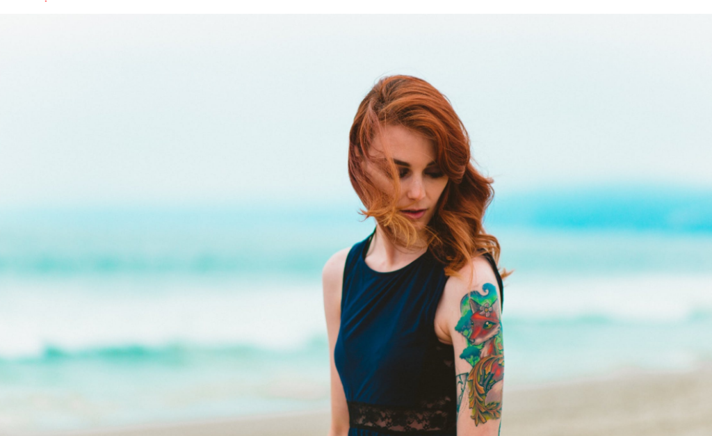 Tattoo Esbjerg kvinde der står foran havet med sin nye tatovering i Esbjerg